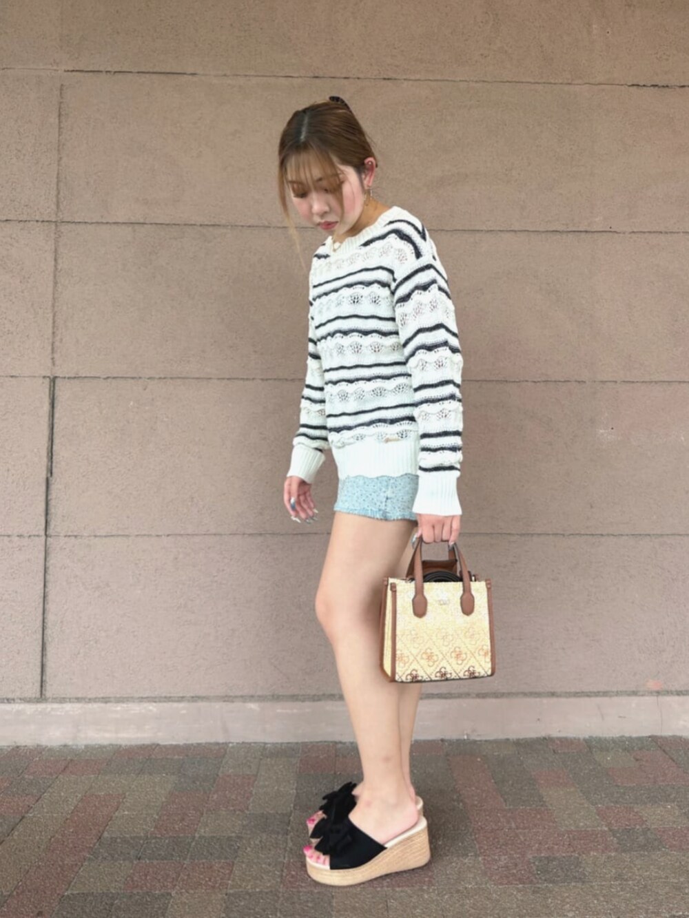 ホワイト系のニット/セーター、ブラウン系のショルダーバッグ、ブルー系のデニムパンツを着用したレディースの夏コーディネートの3枚目の写真