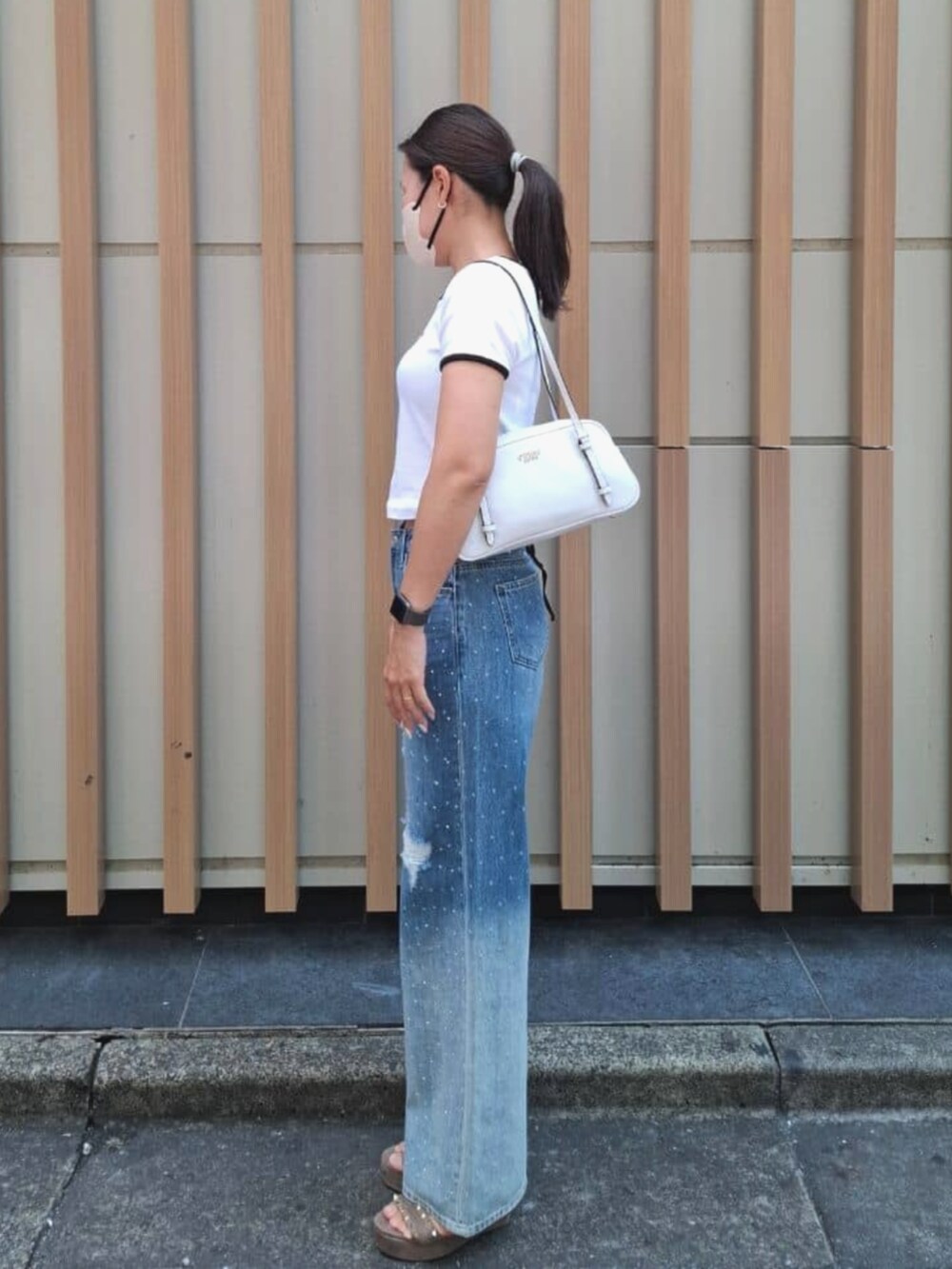ホワイト系のショルダーバッグ、ホワイト系のTシャツ/カットソー、ブルー系のデニムパンツを着用したレディースの夏コーディネートの3枚目の写真