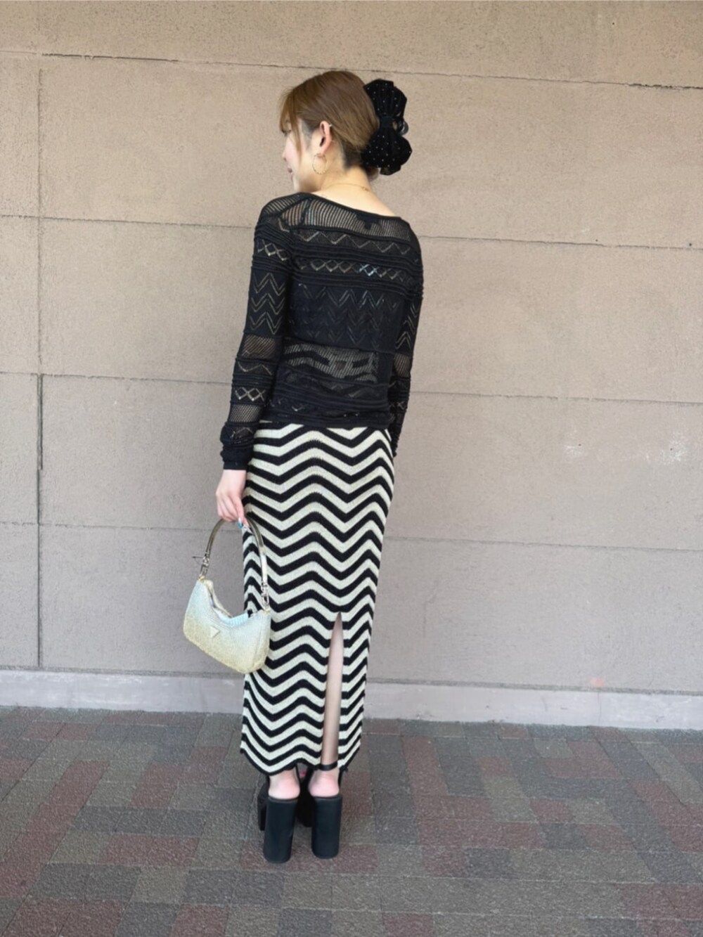 ゴールド系のハンドバッグ、ブラック系のワンピース、ブラック系のカーディガン/ボレロを着用したレディースの秋コーディネートの2枚目の写真