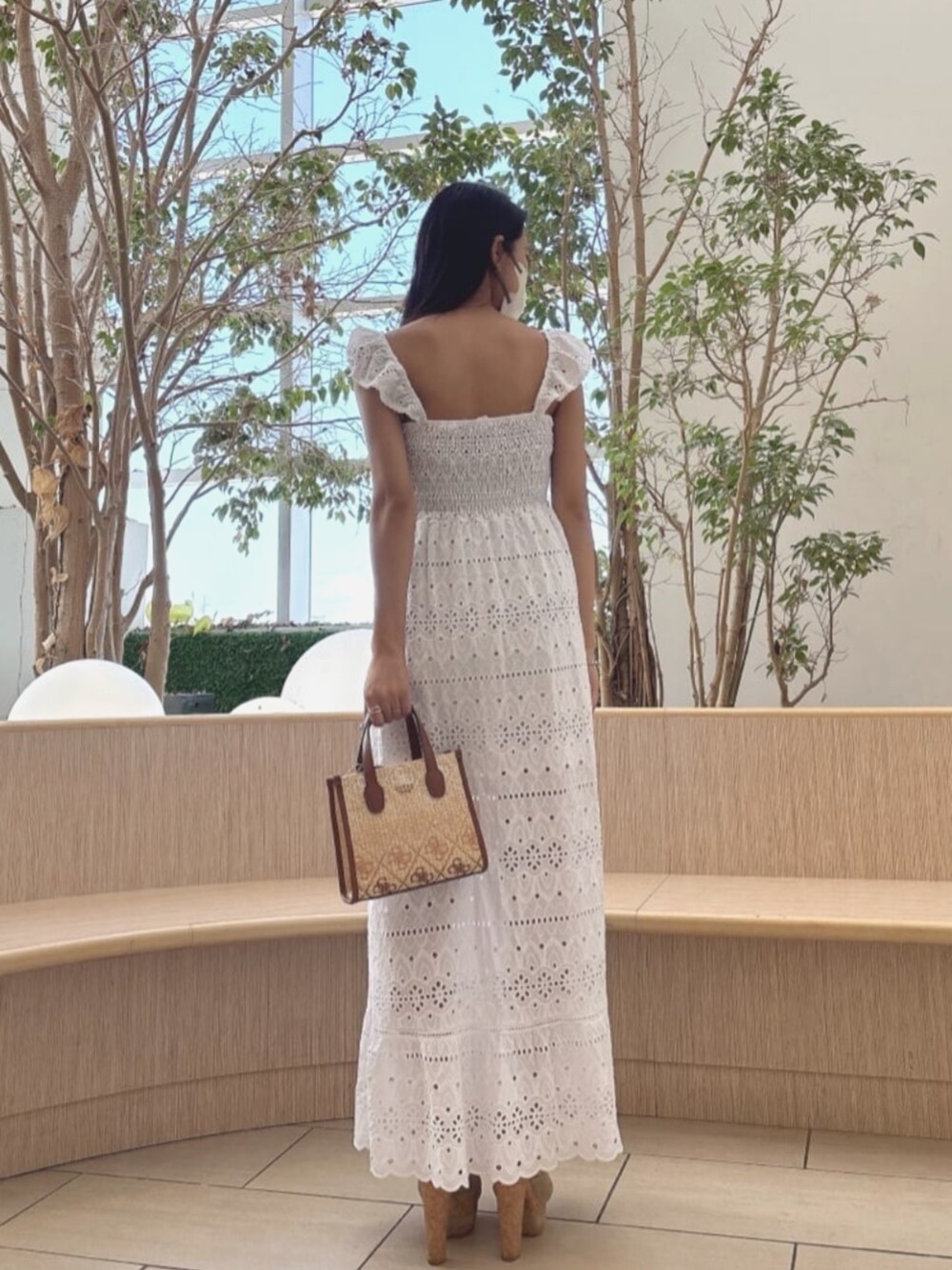 ブラウン系のショルダーバッグ、ホワイト系のワンピースを着用したレディースの夏コーディネートの2枚目の写真