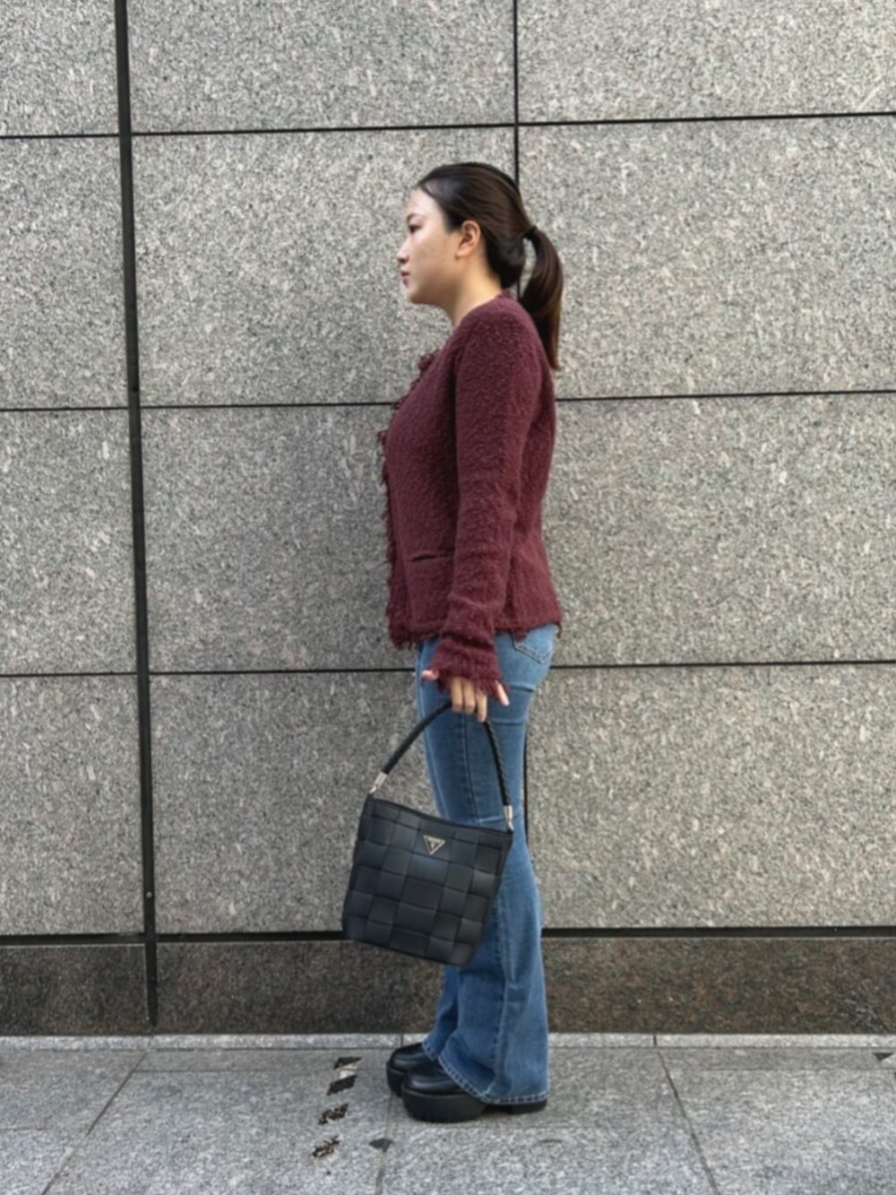 ブルー系のデニムパンツ、レッド系のノーカラージャケット、ブラック系のショルダーバッグを着用したレディースの秋コーディネートの3枚目の写真