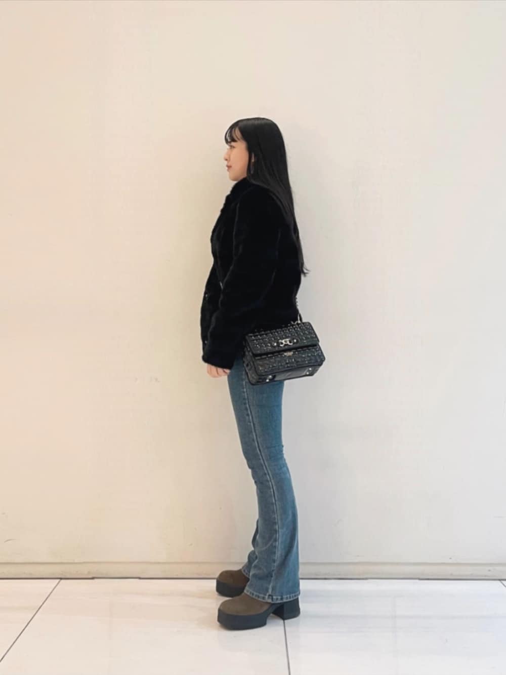 ブルー系のデニムパンツ、ホワイト系のスウェット、ブラック系のショルダーバッグを着用したレディースの冬コーディネートの3枚目の写真