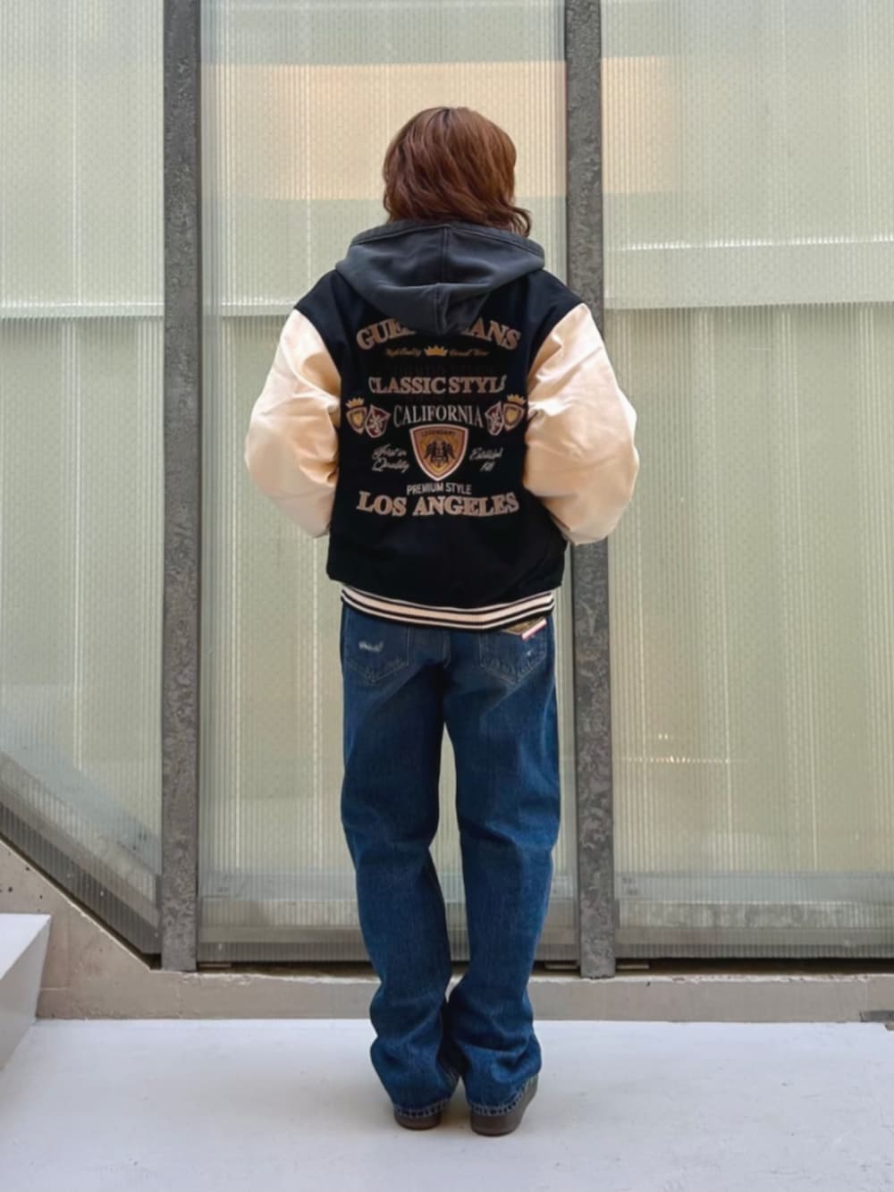 ブルー系のデニムパンツ、ブラック系のパーカー、ブラック系のスタジャンを着用したレディースの冬コーディネートの2枚目の写真