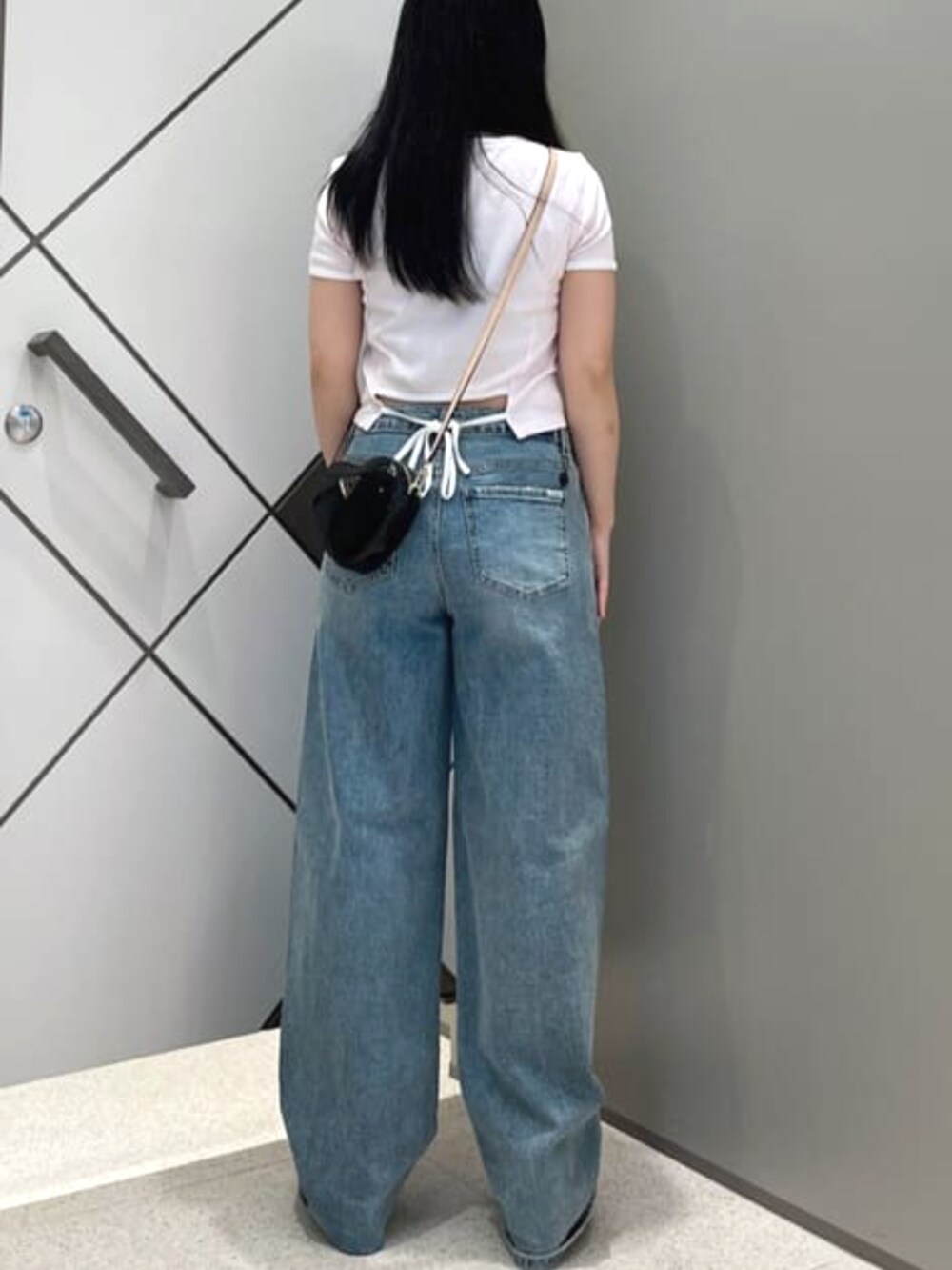 ブラック系のショルダーバッグ、ブルー系のデニムパンツ、ピンク系のTシャツ/カットソーを着用したレディースの夏コーディネートの2枚目の写真