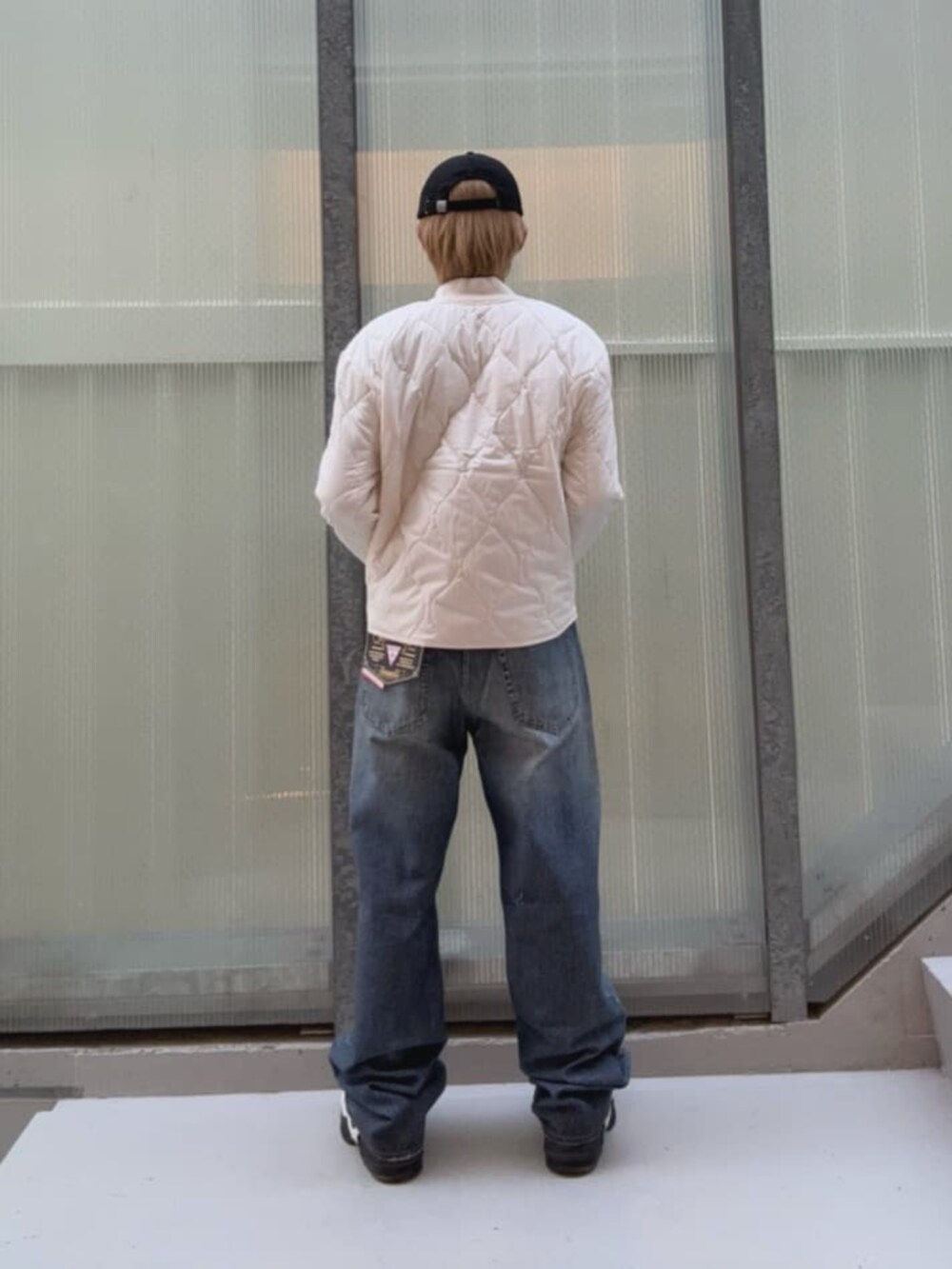 ブルー系のデニムパンツ、ホワイト系のその他アウター、ブラック系のキャップを着用したメンズの秋コーディネートの3枚目の写真