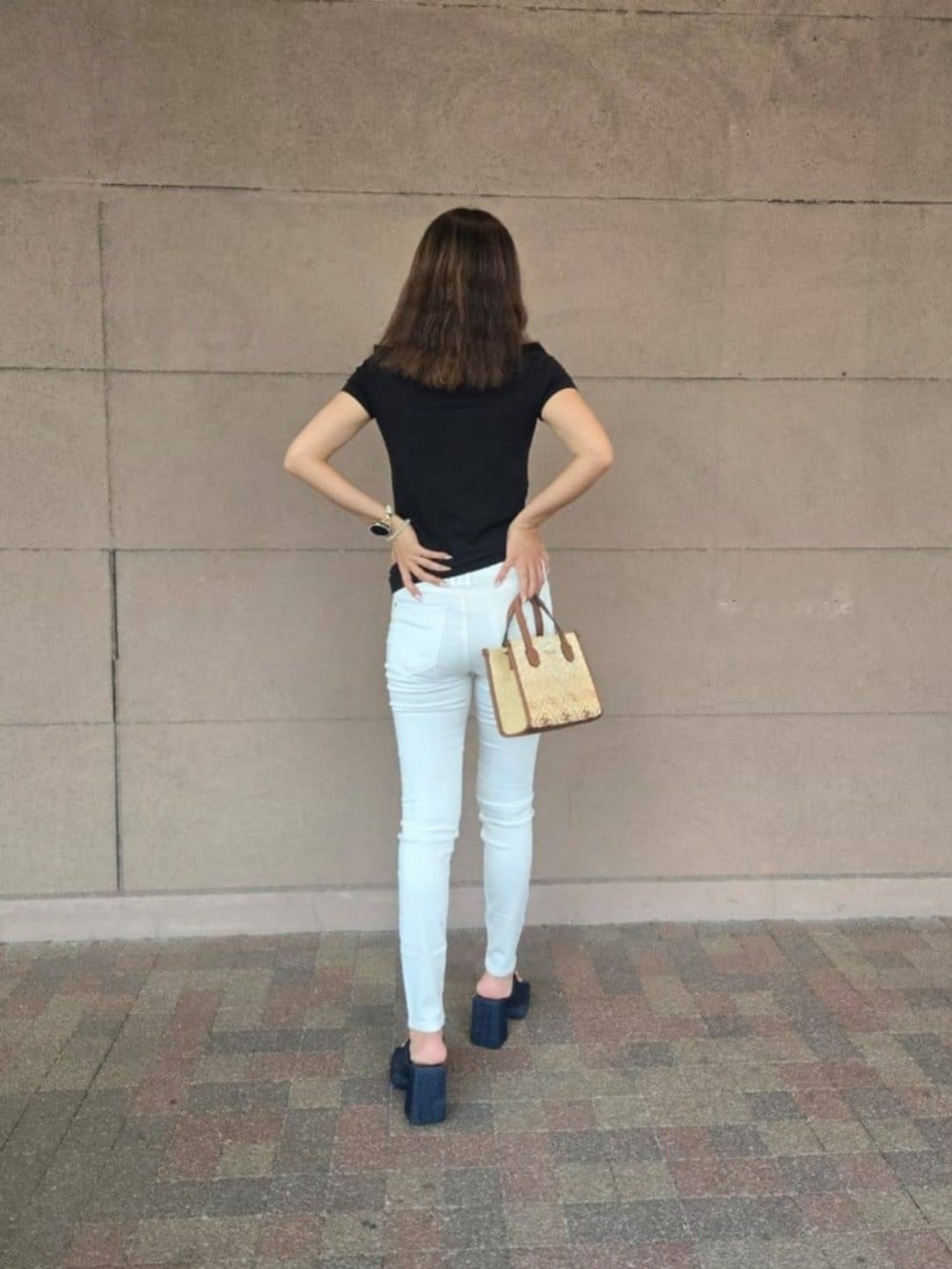 ブラウン系のショルダーバッグ、ホワイト系のデニムパンツ、ブラック系のTシャツ/カットソーを着用したレディースの秋コーディネートの2枚目の写真