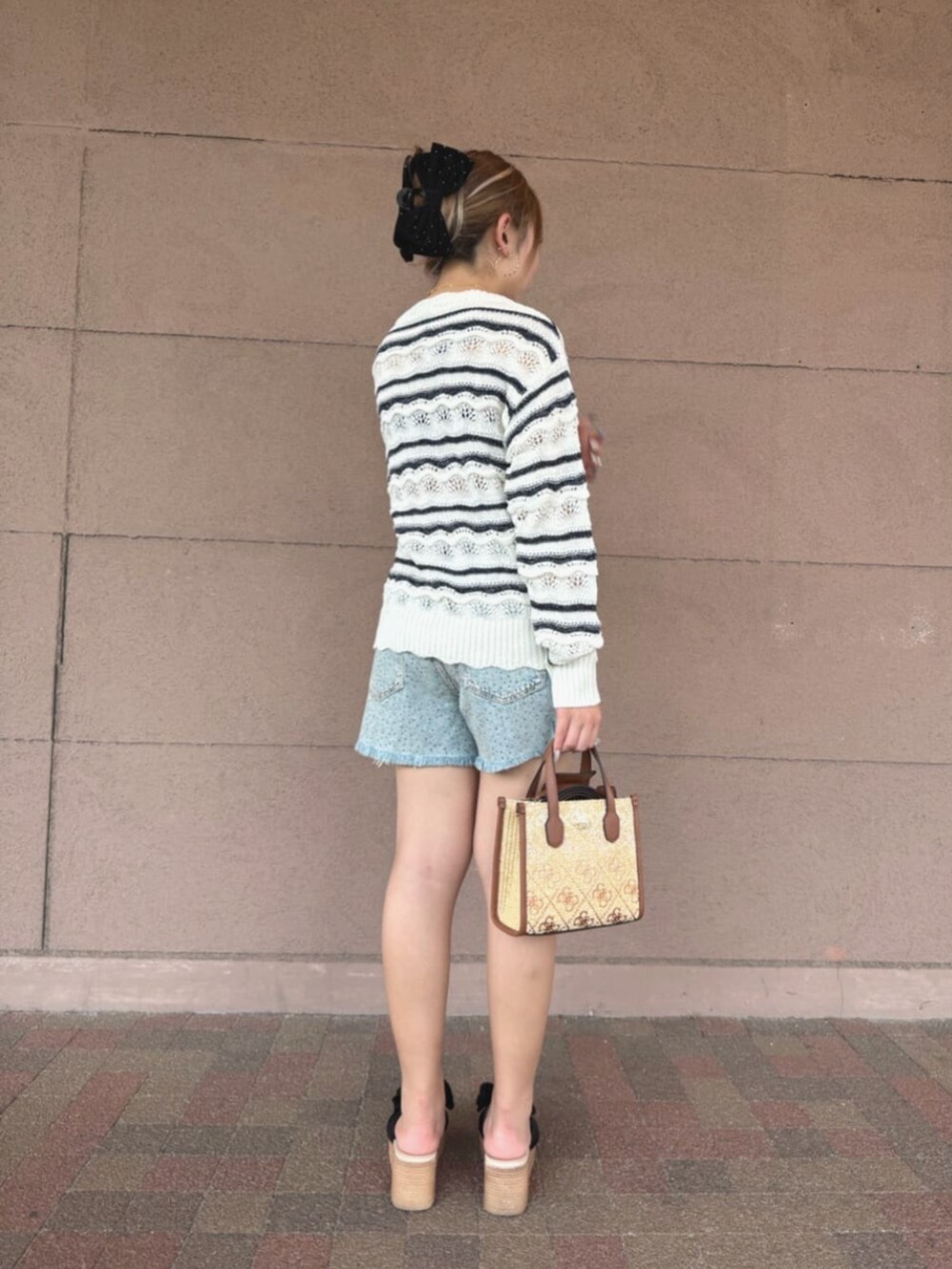 ホワイト系のニット/セーター、ブラウン系のショルダーバッグ、ブルー系のデニムパンツを着用したレディースの夏コーディネートの2枚目の写真