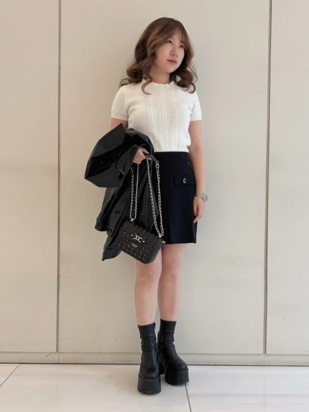 ホワイト系のニット/セーター、ブラック系のスカート、ブラック系のカバーオールを着用したレディースの冬コーディネートの4枚目の写真