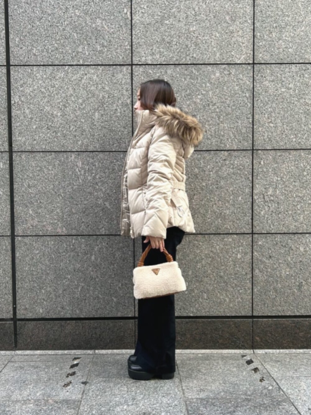 ブラック系のデニムパンツ、ベージュ系のダウンジャケット/コート、イエロー系のショルダーバッグを着用したレディースの冬コーディネートの3枚目の写真