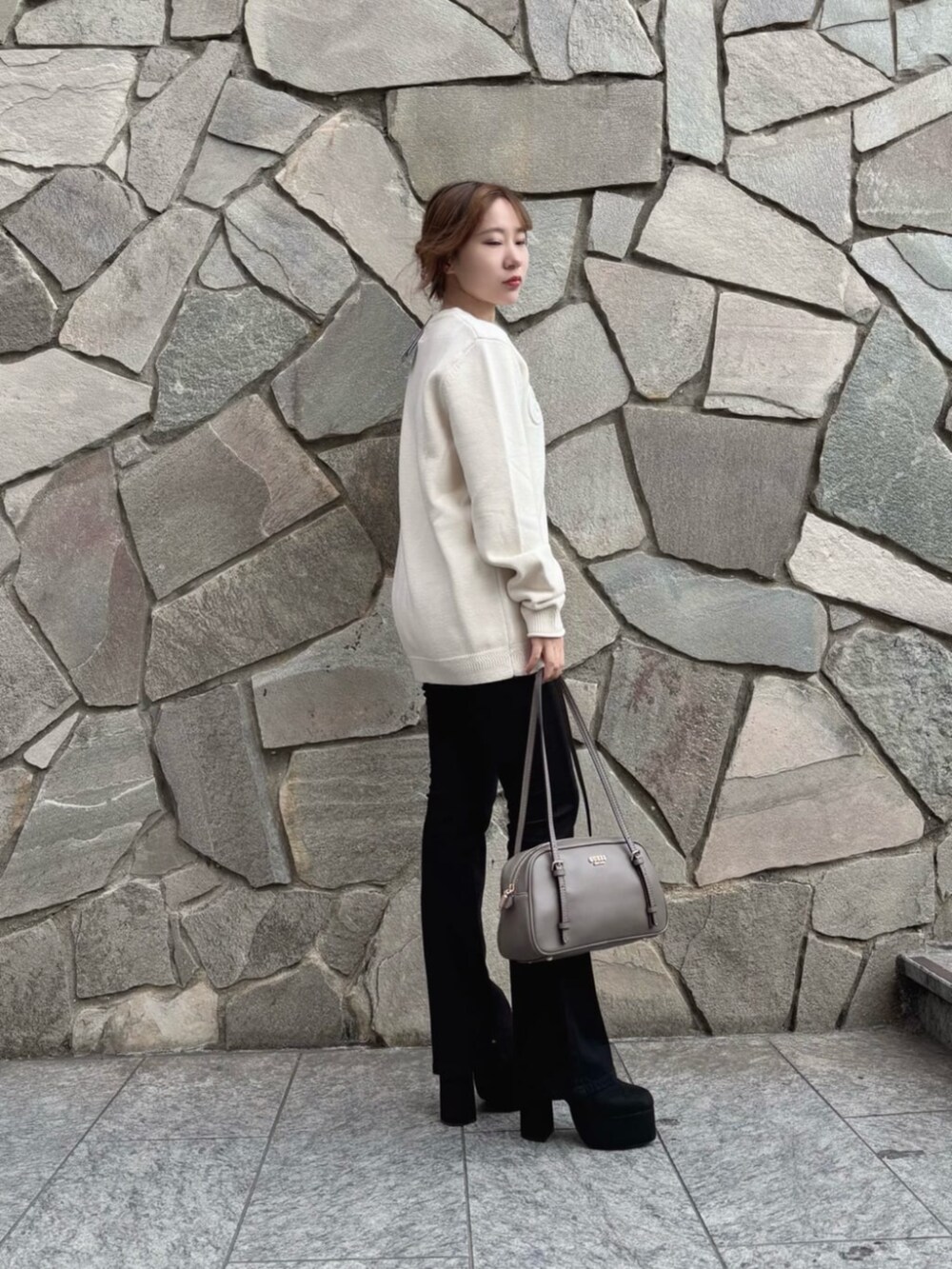 ブラック系のデニムパンツ、ベージュ系のショルダーバッグ、ホワイト系のニット/セーターを着用したレディースの秋コーディネートの3枚目の写真