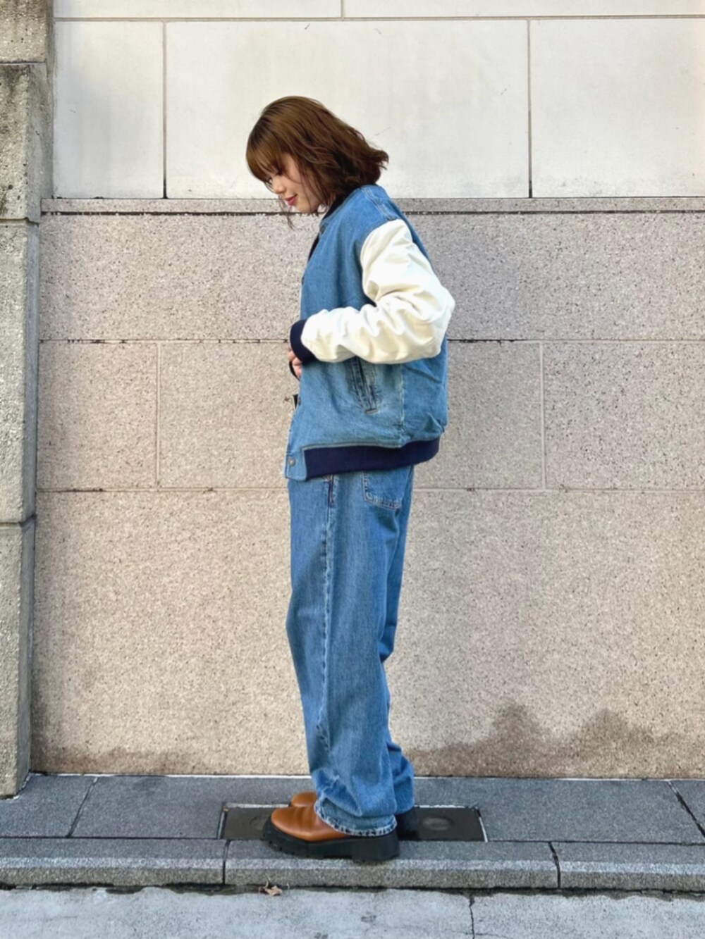 ブルー系のデニムパンツ、ブルー系のスタジャン、ホワイト系のニット/セーターを着用したレディースの冬コーディネートの3枚目の写真