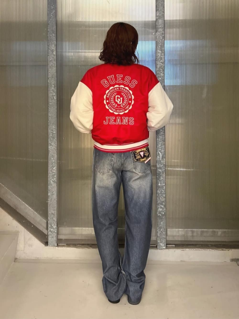 ホワイト系のTシャツ/カットソー、ブルー系のデニムパンツ、レッド系のスタジャンを着用したレディースの秋コーディネートの2枚目の写真