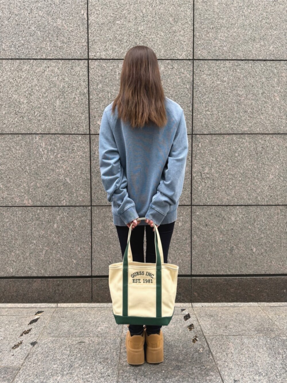 ブルー系のデニムパンツ、グリーン系のトートバッグ、ブルー系のスウェットを着用したレディースの秋コーディネートの2枚目の写真