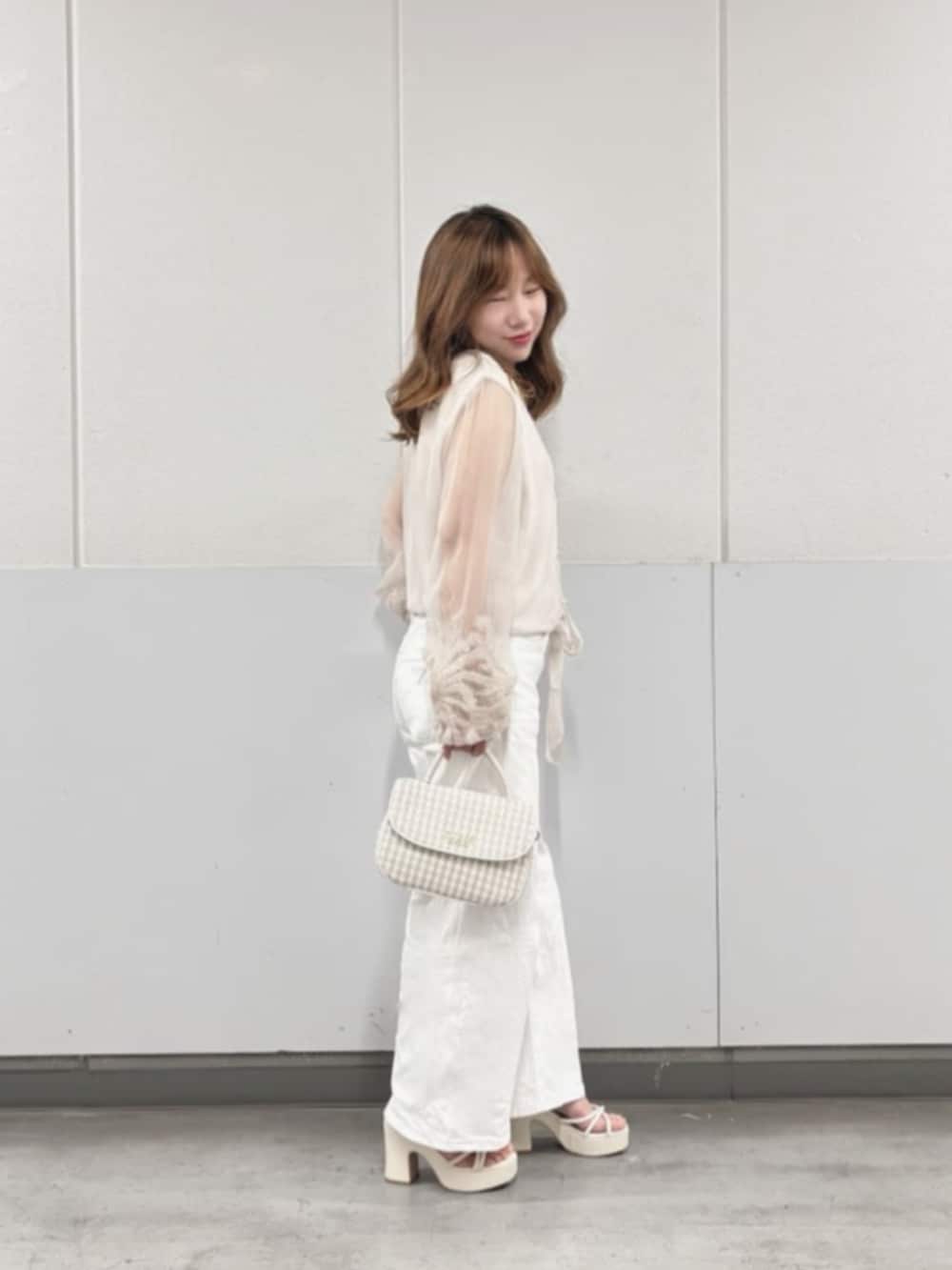 ホワイト系のデニムパンツ、ベージュ系のシャツ/ブラウス、ホワイト系のショルダーバッグを着用したレディースの秋コーディネートの3枚目の写真