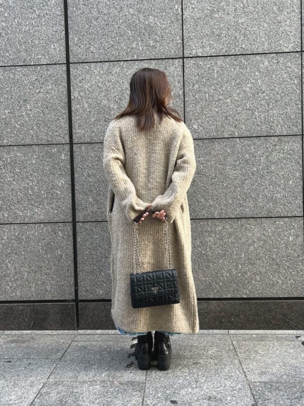 ブラック系のショルダーバッグ、ブルー系のデニムスカート、ホワイト系のニット/セーターを着用したレディースの秋コーディネートの2枚目の写真