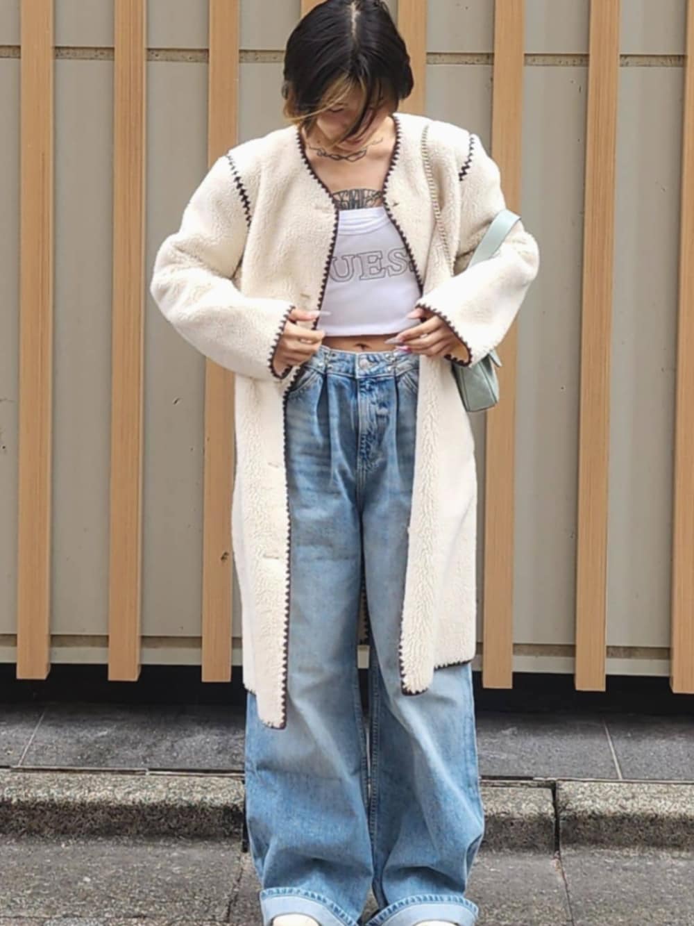 ホワイト系のタンクトップ、ブルー系のデニムパンツ、ホワイト系のノーカラージャケットを着用したレディースの冬コーディネートの5枚目の写真