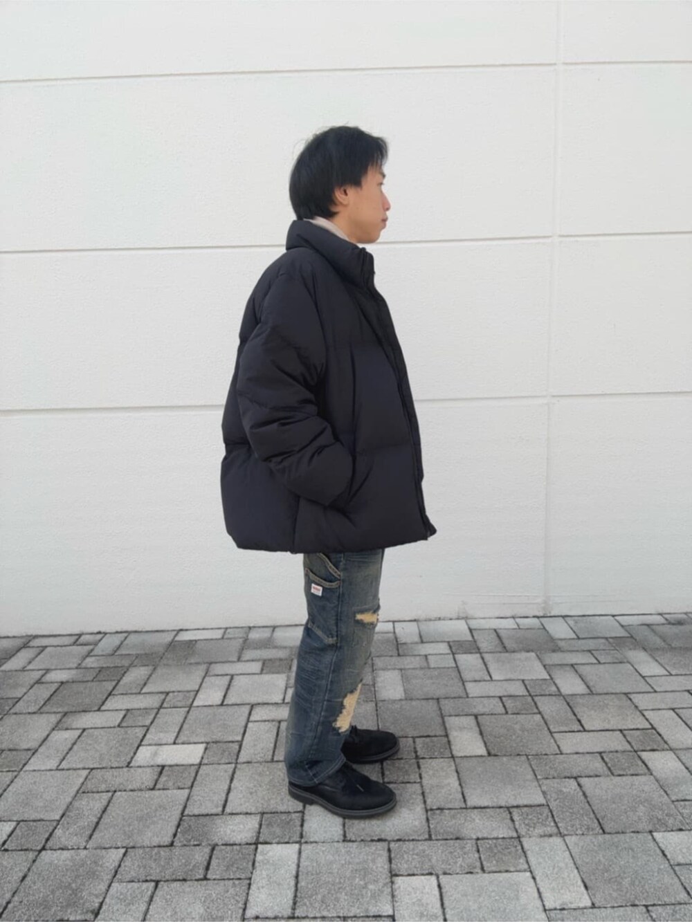 ブラック系のダウンジャケット/コート、ブラック系のニット/セーター、ベージュ系のマフラーを着用したメンズの秋コーディネートの3枚目の写真