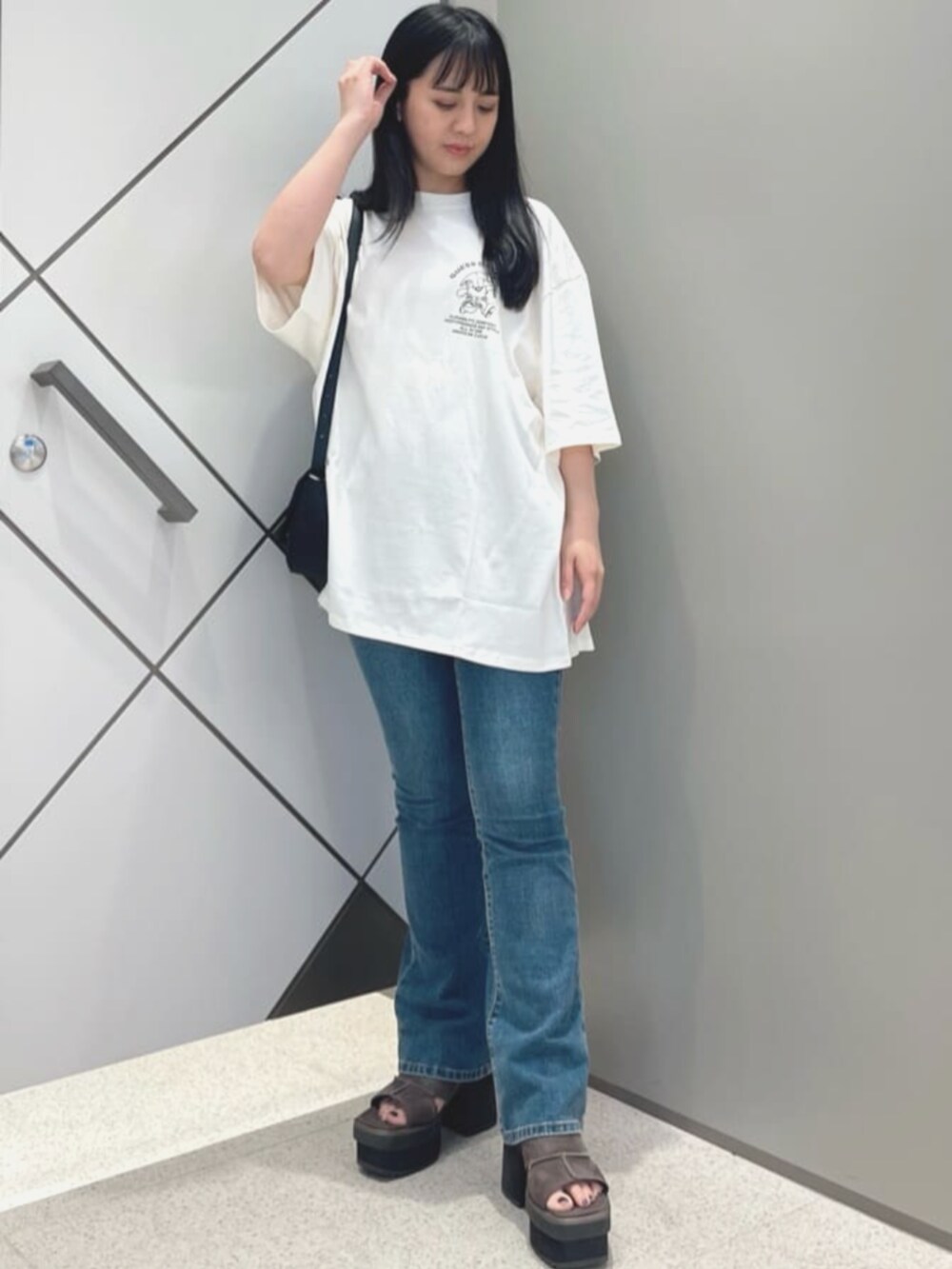 ブルー系のデニムパンツ、ブラック系のショルダーバッグ、ホワイト系のTシャツ/カットソーを着用したレディースの夏コーディネートの4枚目の写真