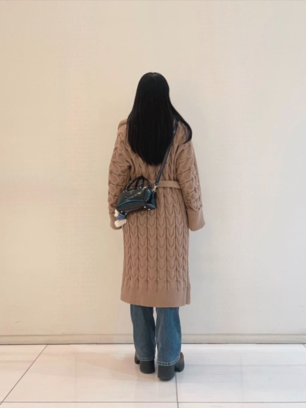 ブルー系のデニムパンツ、ホワイト系のスウェット、ベージュ系のムートンコートを着用したレディースの冬コーディネートの2枚目の写真