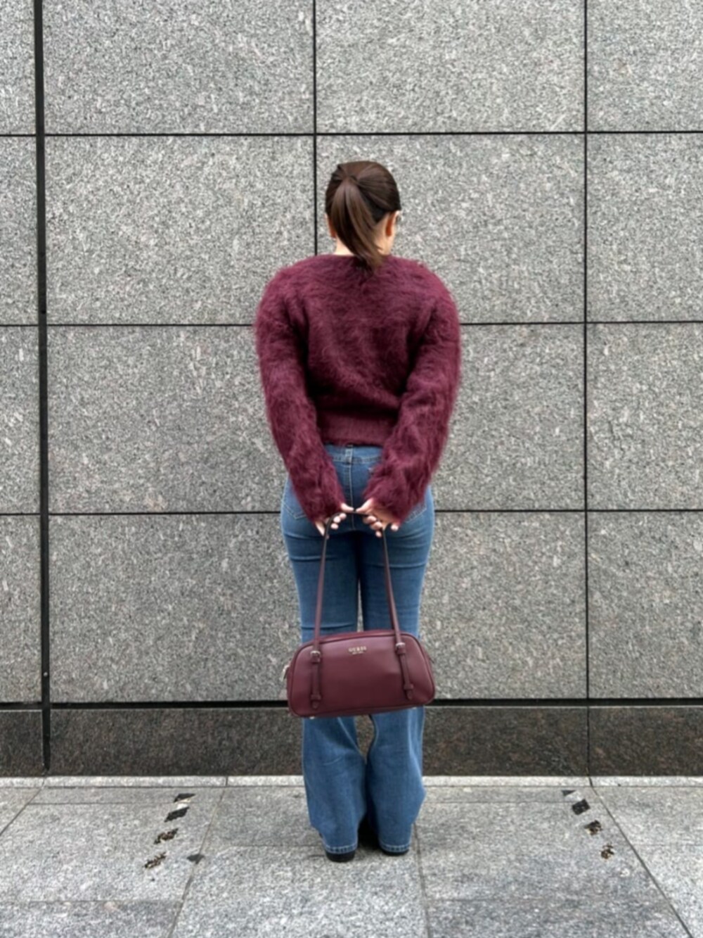 ブルー系のデニムパンツ、レッド系のカーディガン/ボレロ、レッド系のショルダーバッグを着用したレディースの秋コーディネートの2枚目の写真