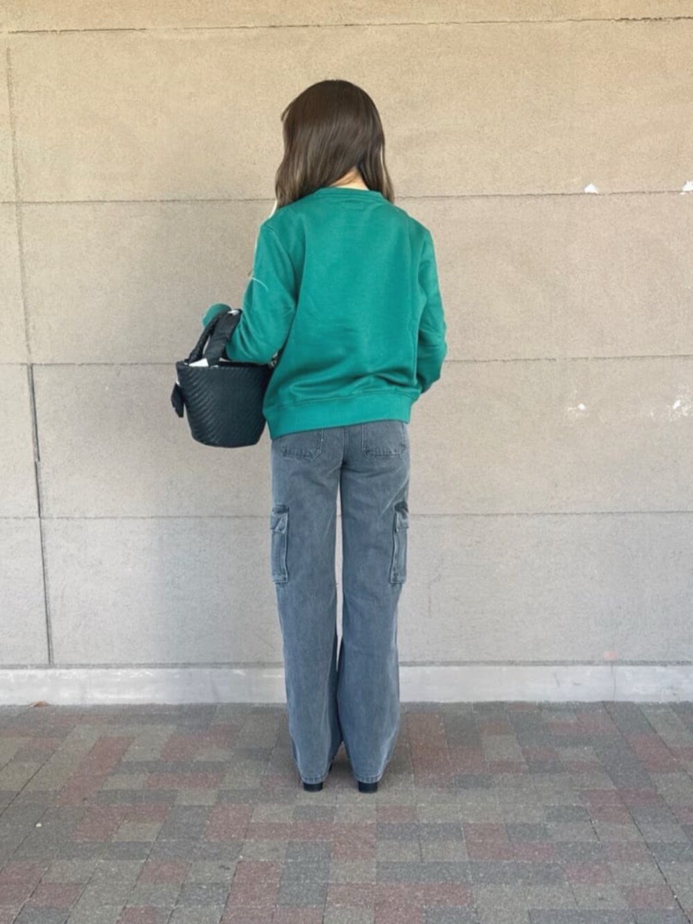 ブラック系のデニムパンツ、グリーン系のスウェット、ブラック系のショルダーバッグを着用したレディースの秋コーディネートの2枚目の写真
