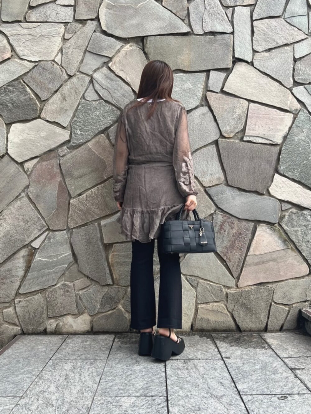 ブラウン系のワンピース、ブラック系のデニムパンツ、ブラック系のショルダーバッグを着用したレディースの秋コーディネートの2枚目の写真