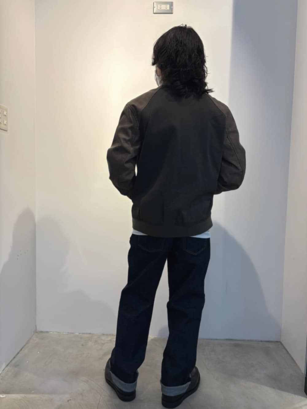 ブルー系のデニムパンツ、グレー系のニット/セーター、グリーン系のブルゾンを着用したメンズの冬コーディネートの2枚目の写真