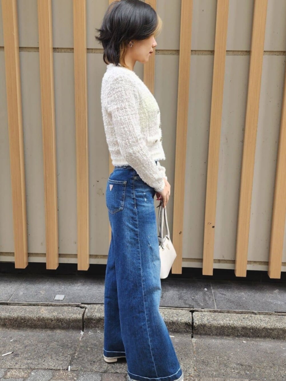 ホワイト系のショルダーバッグ、ブルー系のデニムパンツ、ホワイト系のカーディガン/ボレロを着用したレディースの冬コーディネートの4枚目の写真