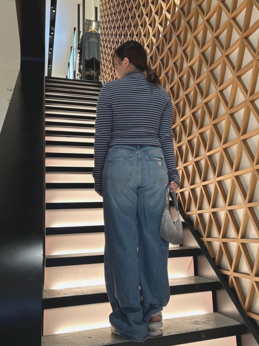 ブルー系のニット/セーター、シルバー系のハンドバッグ、ブルー系のデニムパンツを着用したレディースの夏コーディネートの2枚目の写真