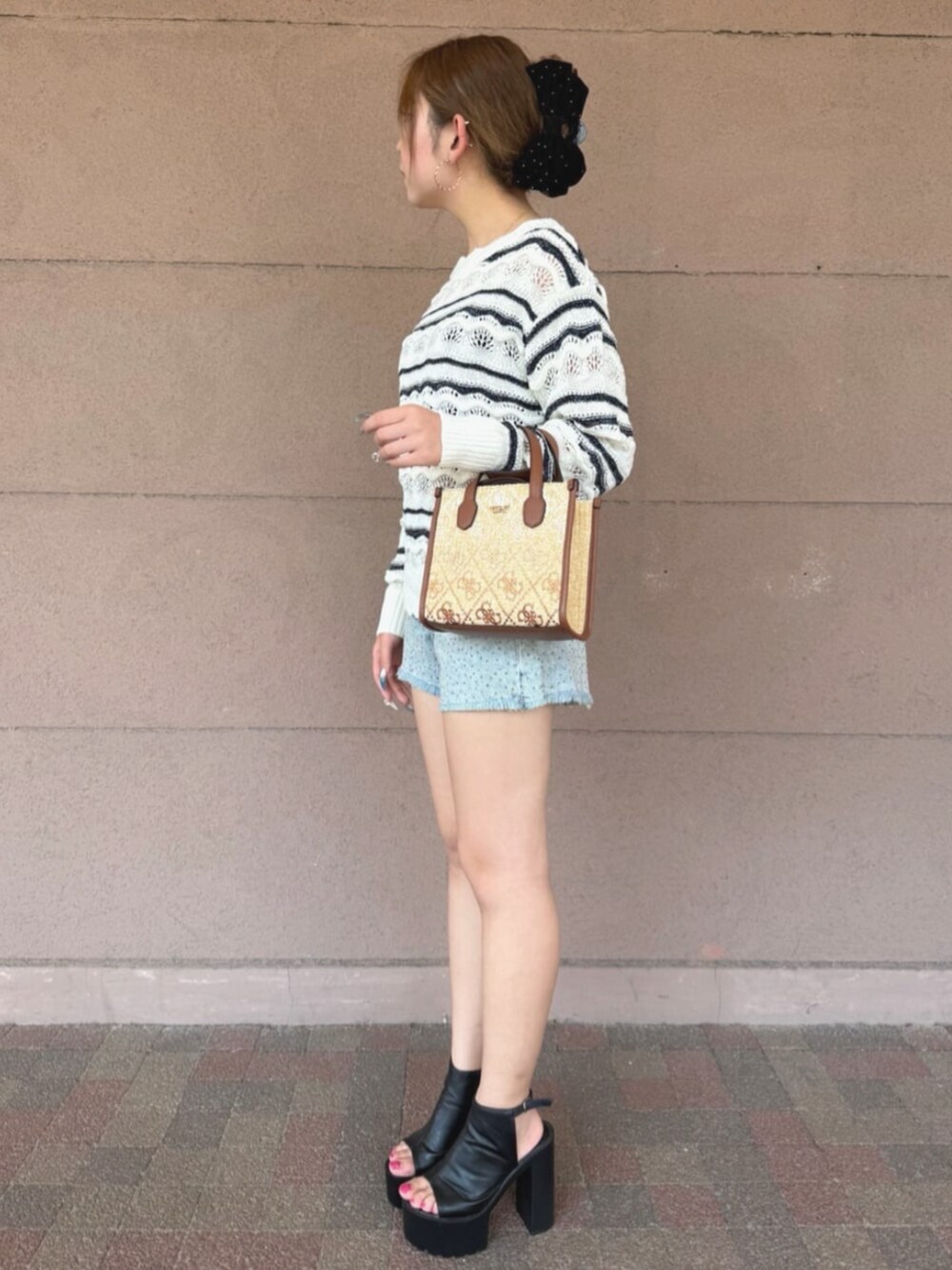ホワイト系のニット/セーター、ブラウン系のショルダーバッグ、ブルー系のデニムパンツを着用したレディースの夏コーディネートの3枚目の写真