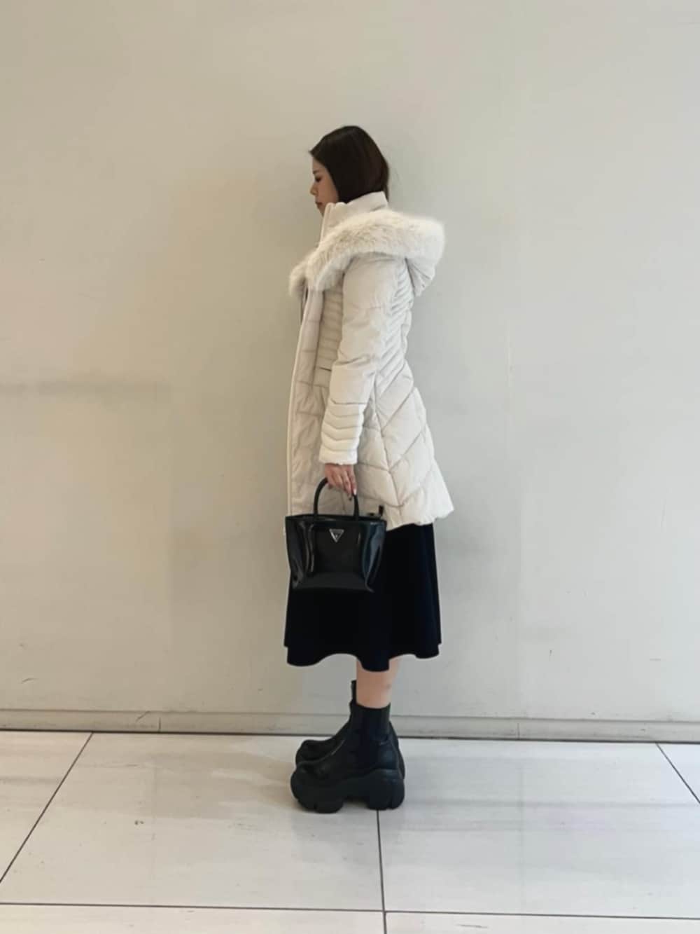 ブラック系のワンピース、ホワイト系のダウンジャケット/コート、ブラック系のトートバッグを着用したレディースの冬コーディネートの3枚目の写真