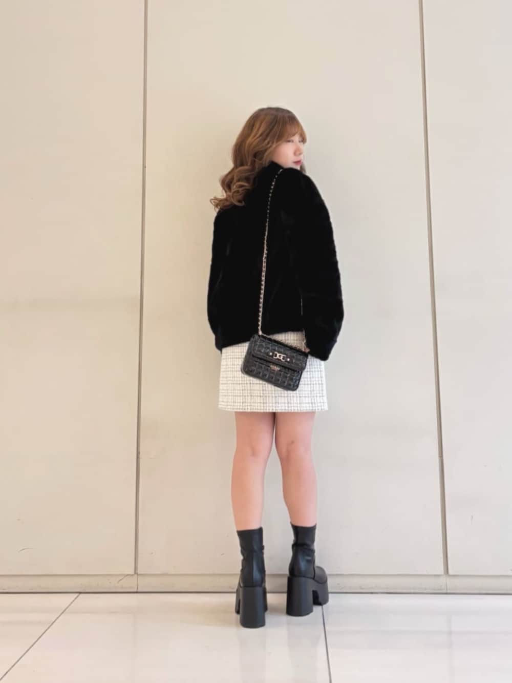 ホワイト系のスカート、ブラック系のショルダーバッグ、ブラック系のその他アウターを着用したレディースの冬コーディネートの2枚目の写真