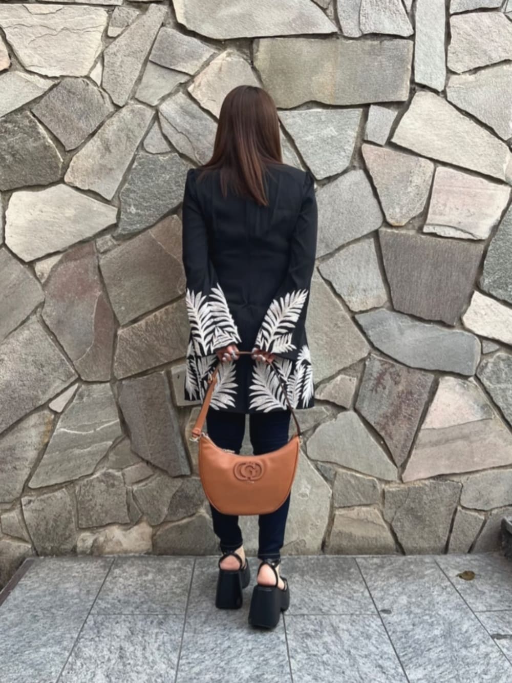 ブルー系のデニムパンツ、ブラック系のワンピース、ブラウン系のショルダーバッグを着用したレディースの秋コーディネートの2枚目の写真