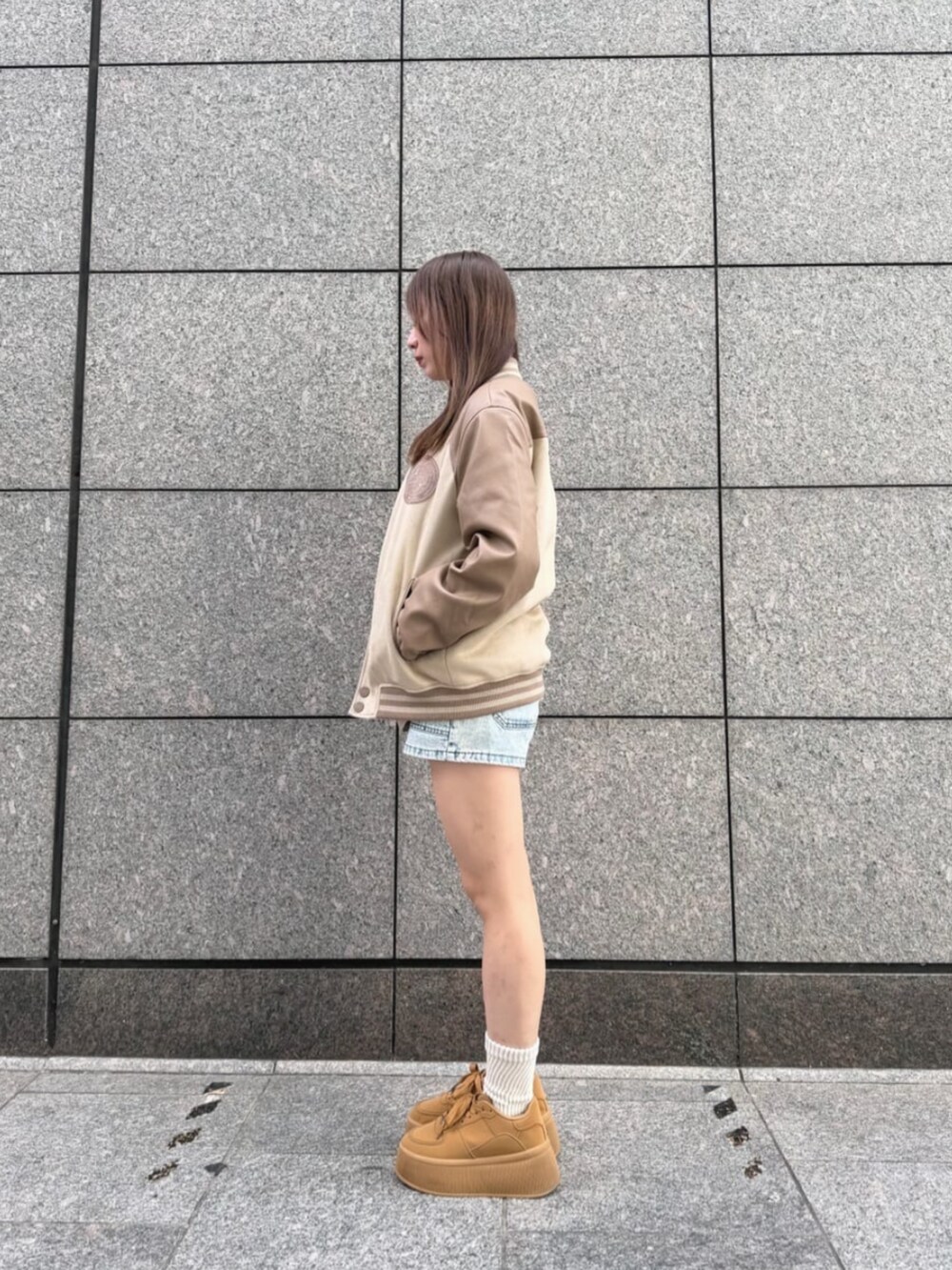 ブルー系のデニムパンツ、ベージュ系のTシャツ/カットソー、ベージュ系のスタジャンを着用したレディースの秋コーディネートの3枚目の写真