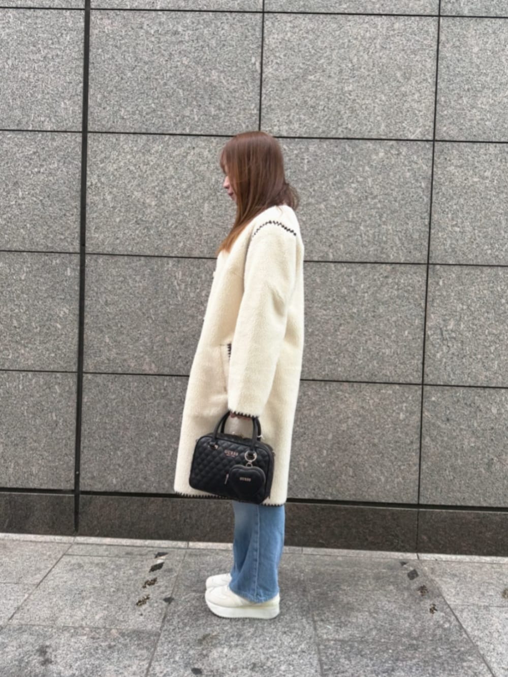 ブルー系のデニムパンツ、ブルー系のニット/セーター、ホワイト系のノーカラージャケットを着用したレディースの冬コーディネートの3枚目の写真