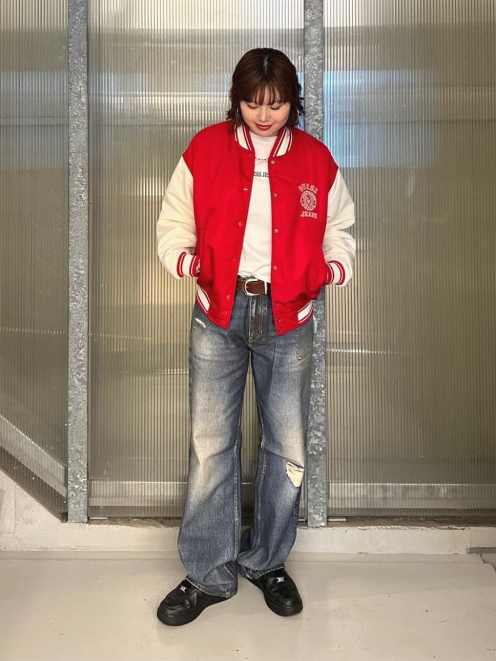 ホワイト系のTシャツ/カットソー、ブルー系のデニムパンツ、レッド系のスタジャンを着用したレディースの秋コーディネートの4枚目の写真