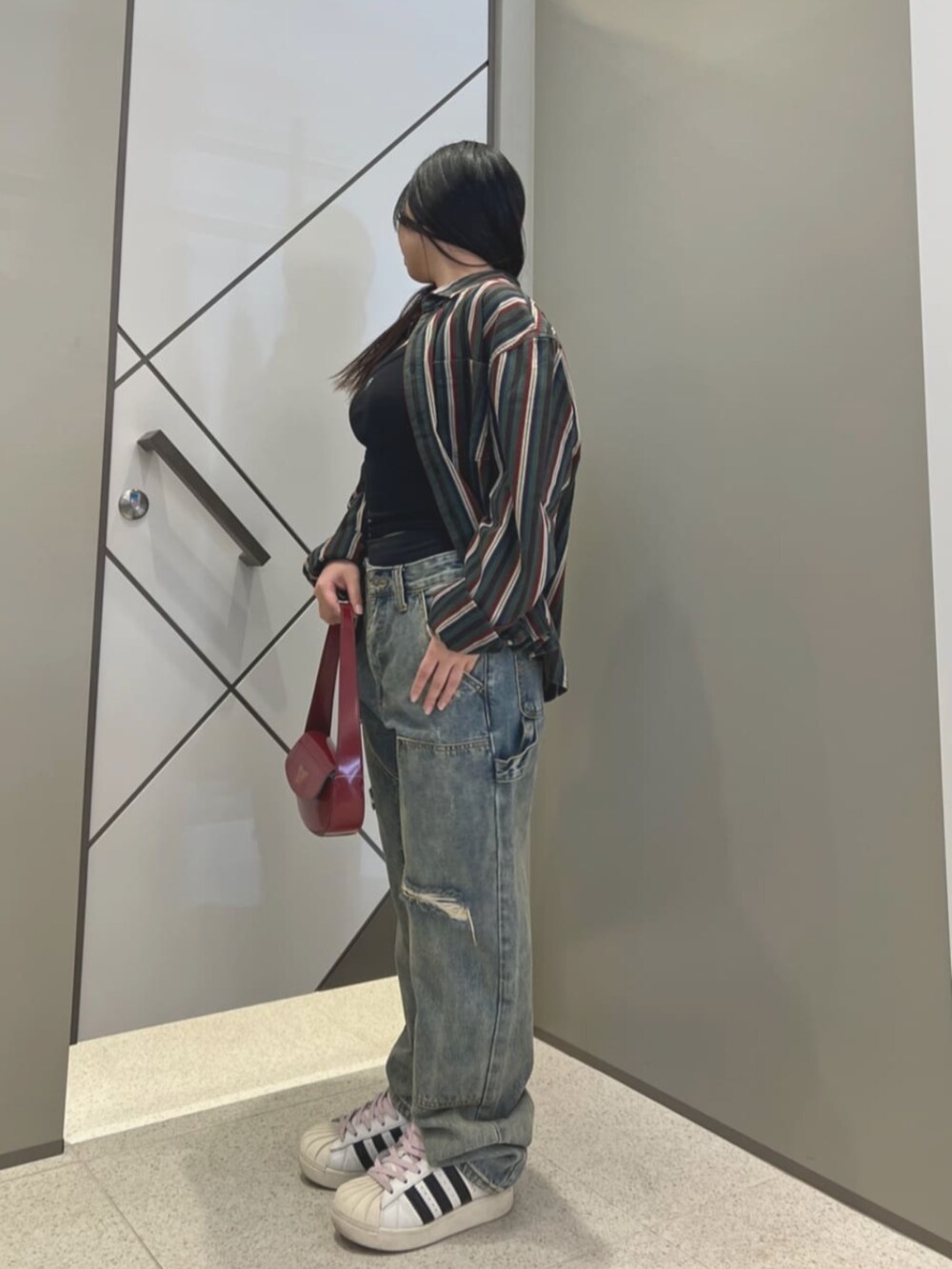 ブラック系のタンクトップ、ブルー系のデニムパンツを着用したレディースの夏コーディネートの3枚目の写真