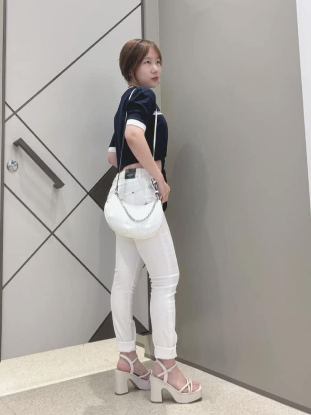 ブルー系のTシャツ/カットソー、ホワイト系のデニムパンツ、ホワイト系のハンドバッグを着用したレディースの夏コーディネートの3枚目の写真