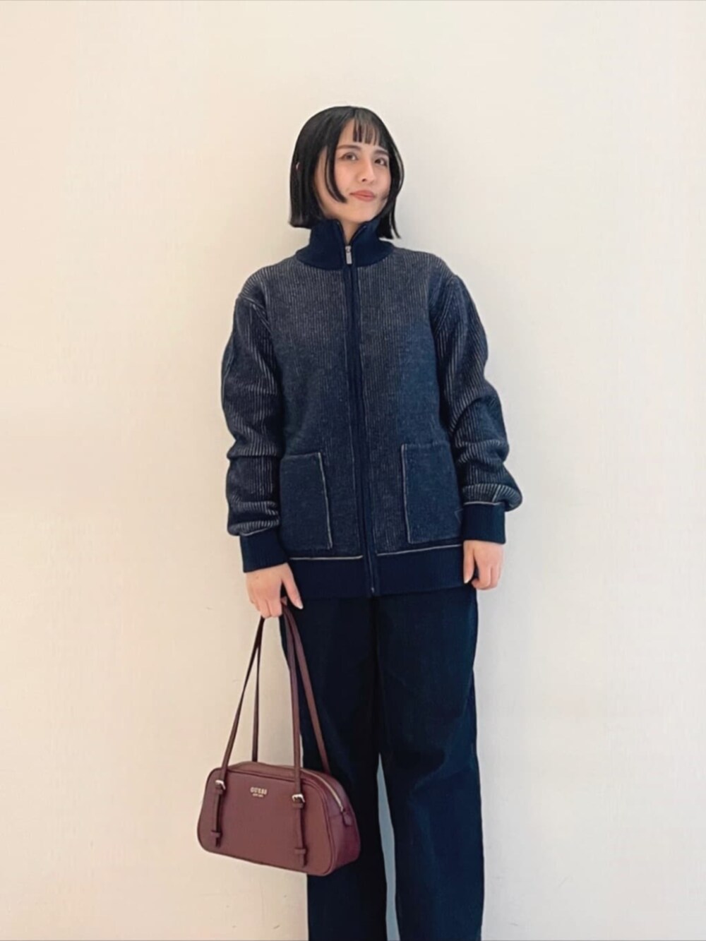 ブラック系のニット/セーター、レッド系のショルダーバッグ、ブルー系のブルゾンを着用したレディースの冬コーディネートの4枚目の写真