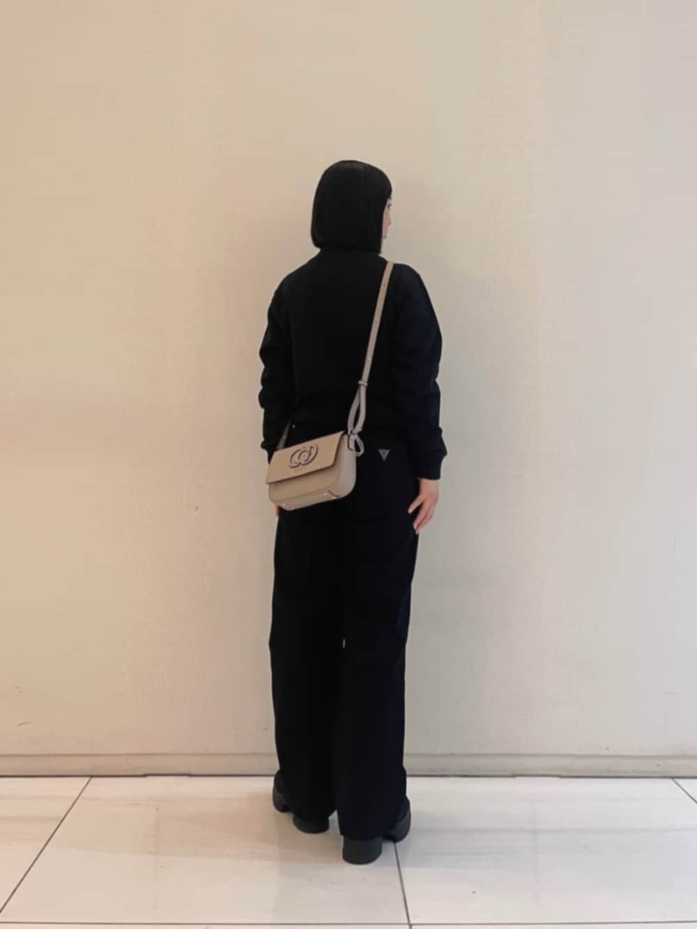 ブラック系のデニムパンツ、ブラック系のスウェット、ベージュ系のショルダーバッグを着用したレディースの冬コーディネートの2枚目の写真