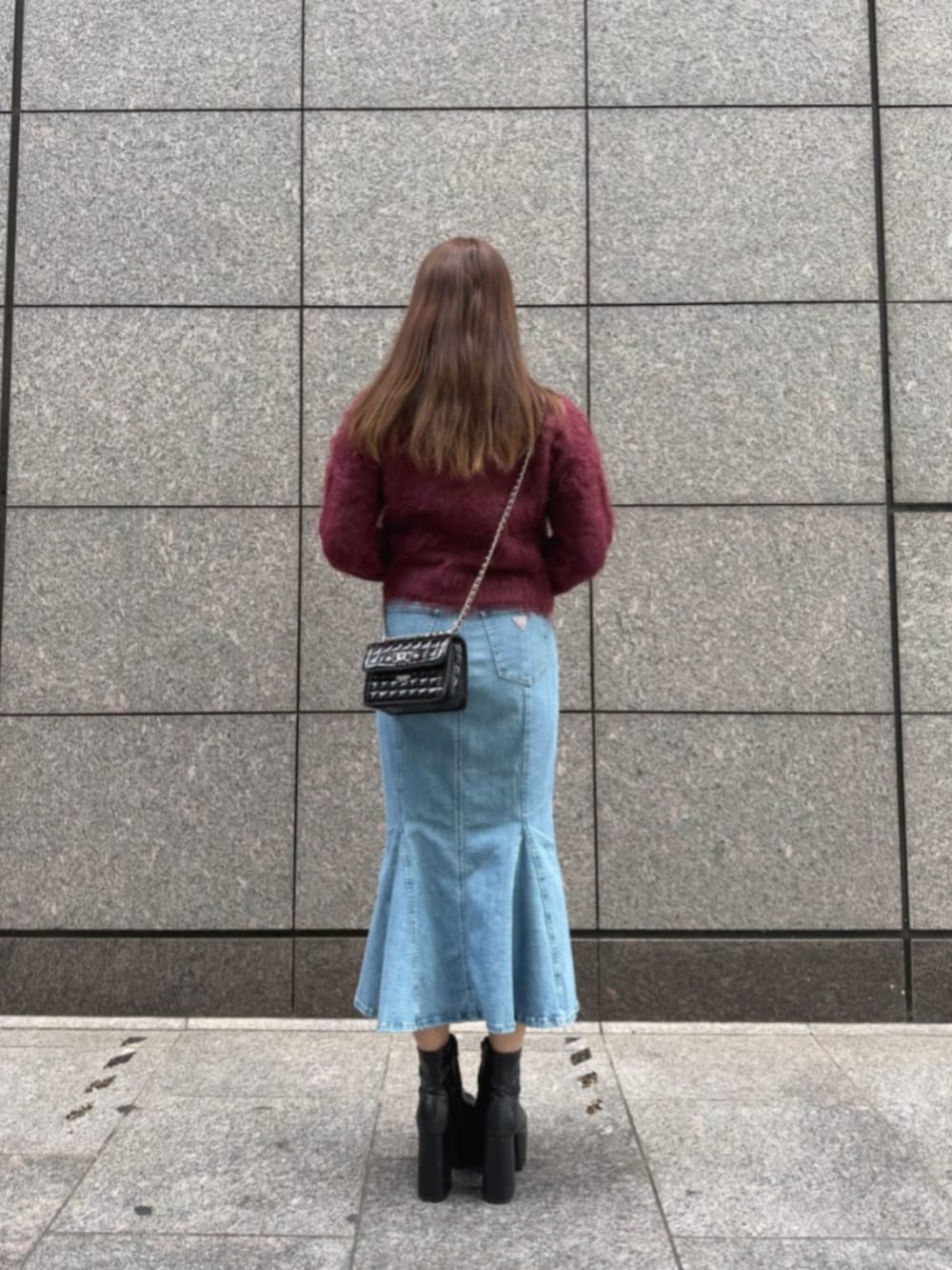 ブルー系のデニムスカート、レッド系のカーディガン/ボレロ、ブラック系のショルダーバッグを着用したレディースの冬コーディネートの2枚目の写真