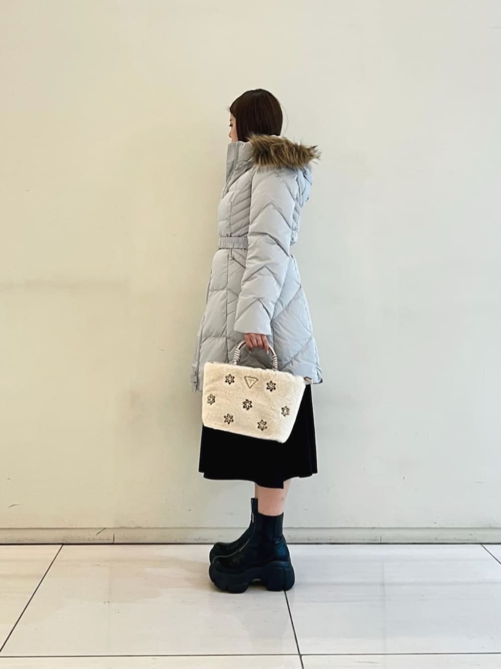 グレー系のダウンジャケット/コート、ブラック系のワンピース、ホワイト系のショルダーバッグを着用したレディースの冬コーディネートの3枚目の写真