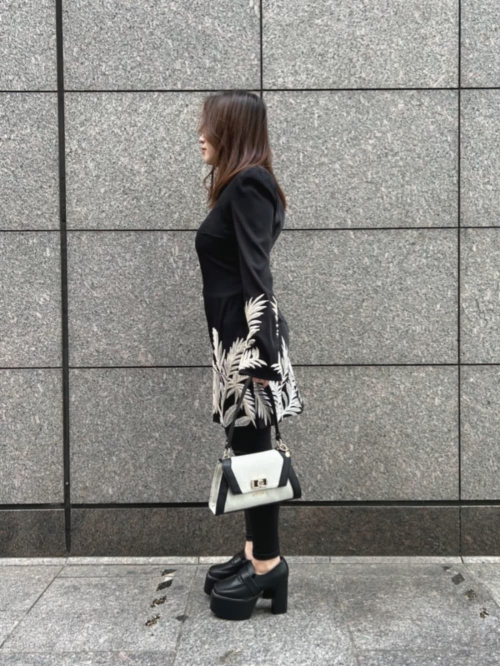 ブラック系のワンピース、ブラック系のショルダーバッグを着用したレディースの冬コーディネートの3枚目の写真