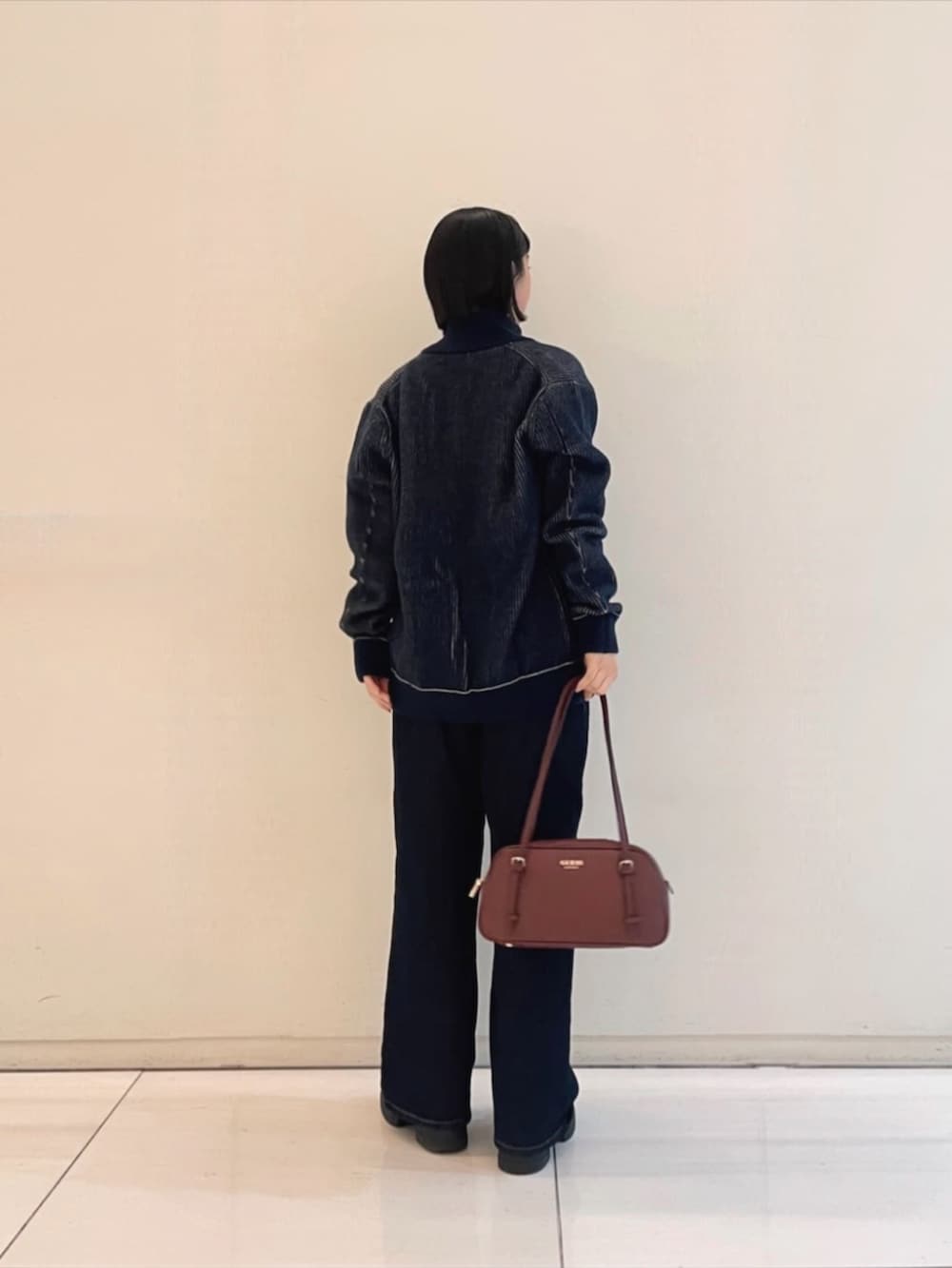 ブラック系のニット/セーター、レッド系のショルダーバッグ、ブルー系のブルゾンを着用したレディースの冬コーディネートの2枚目の写真