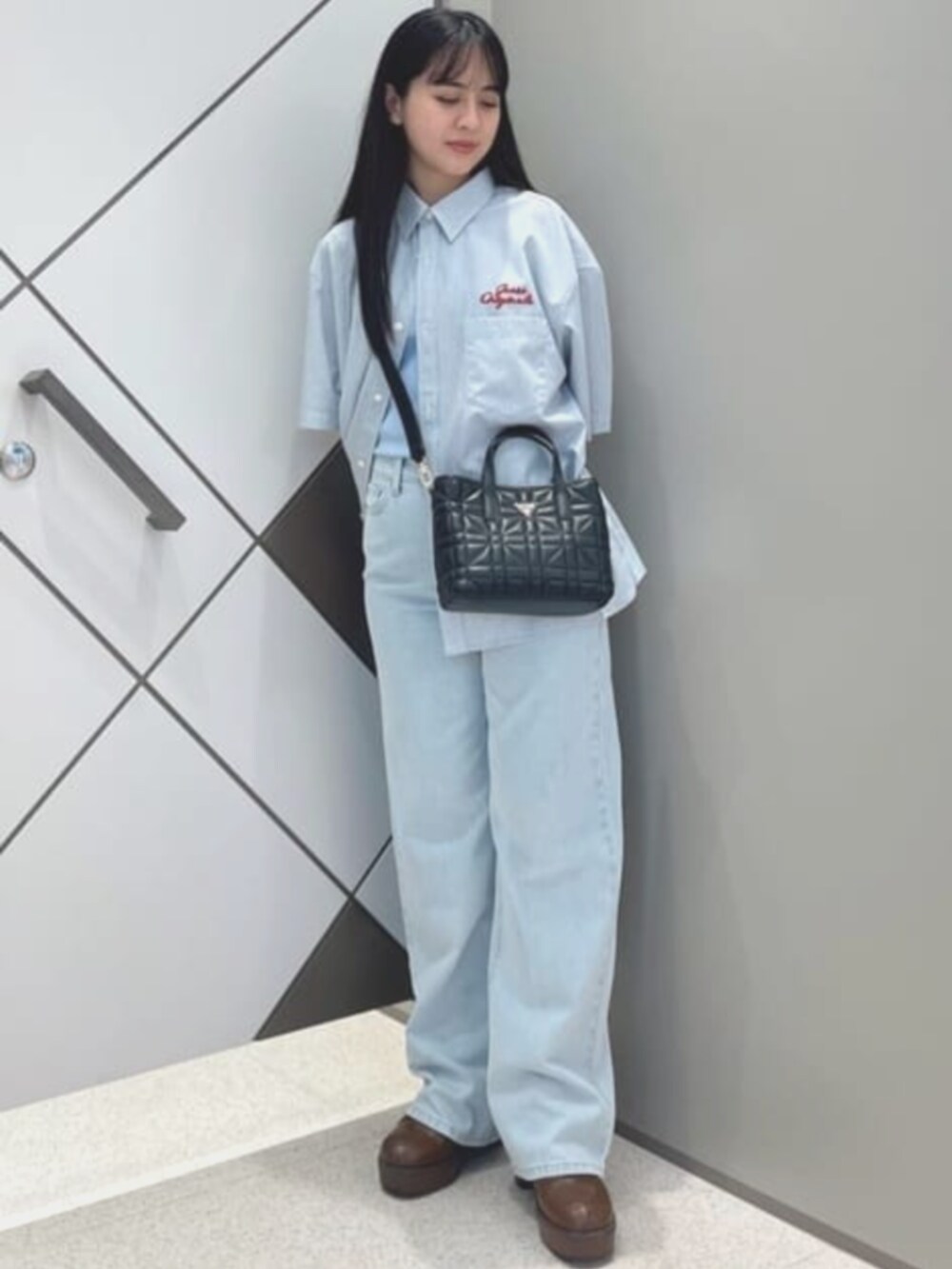 ブルー系のタンクトップ、ブルー系のデニムパンツ、ブラック系のショルダーバッグを着用したレディースの夏コーディネートの4枚目の写真