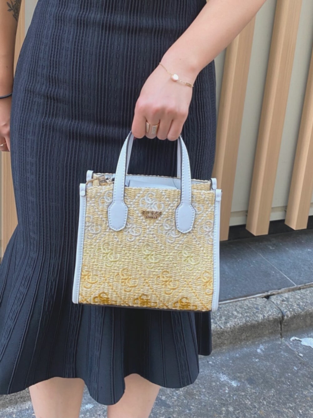 ホワイト系のショルダーバッグ、ブラック系のワンピース、ゴールド系のブレスレットを着用したレディースの夏コーディネートの3枚目の写真