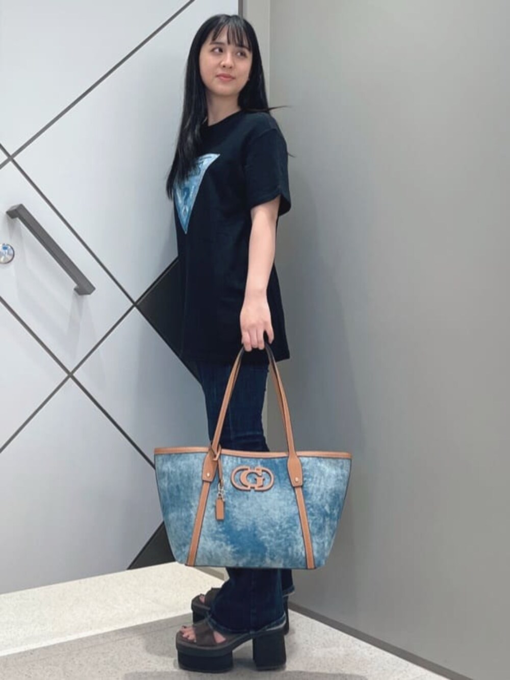 ブルー系のデニムパンツ、ブルー系のトートバッグ、ブラック系のTシャツ/カットソーを着用したレディースの夏コーディネートの3枚目の写真