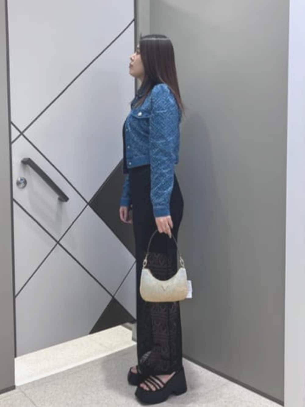 ブルー系のデニムジャケット、ブラック系のワンピース、ゴールド系のハンドバッグを着用したレディースの夏コーディネートの3枚目の写真