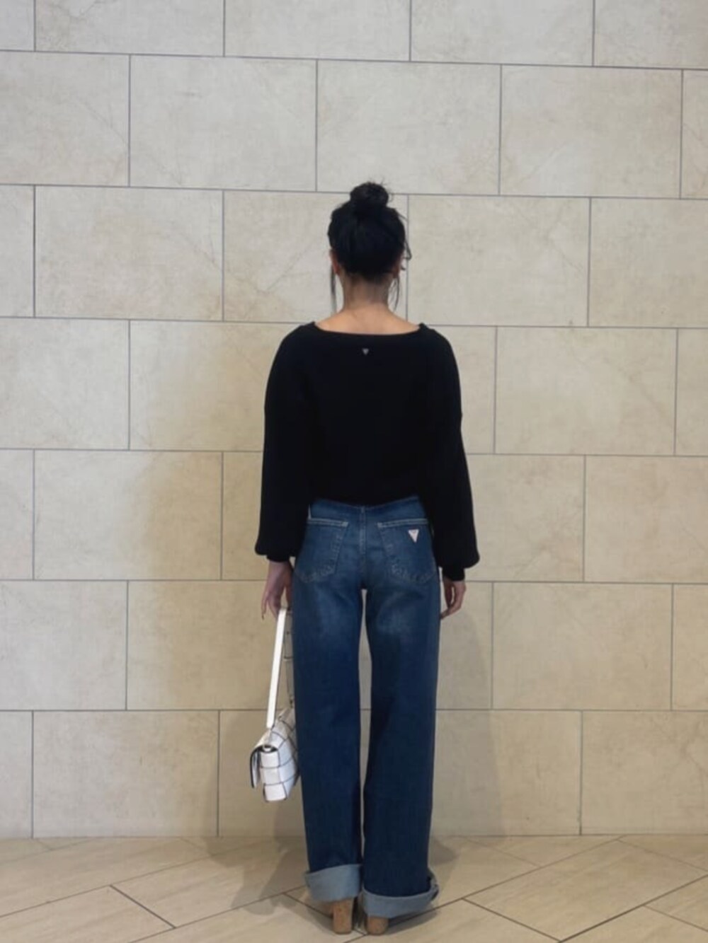 ブルー系のデニムパンツ、ホワイト系のショルダーバッグ、ブラック系のカーディガン/ボレロを着用したレディースの秋コーディネートの2枚目の写真