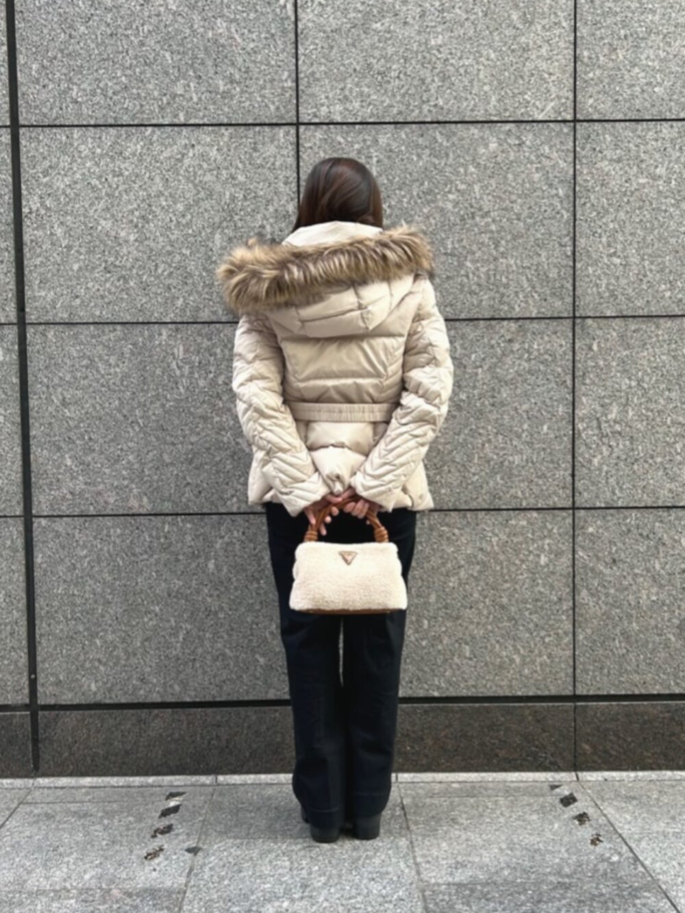 ブラック系のデニムパンツ、ベージュ系のダウンジャケット/コート、イエロー系のショルダーバッグを着用したレディースの冬コーディネートの2枚目の写真